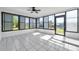 Bright sunroom features white tile flooring, a ceiling fan, and expansive windows showcasing serene canal views with boat dock access at 13836 Darlene Ave, Hudson, FL 34667
