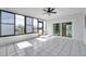Bright sunroom features white tile flooring, a ceiling fan, and expansive windows showcasing serene views at 13836 Darlene Ave, Hudson, FL 34667