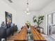 Bright dining room featuring a long wood table with glass inserts, modern light fixture, and stylish decor at 14000 Lugano Ct, Hudson, FL 34669