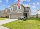 A two-story home has a two-car garage, a manicured lawn, and a covered front entrance with an American flag at 14000 Lugano Ct, Hudson, FL 34669