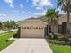 Inviting home featuring a well-manicured lawn, palm trees, and a two-car garage at 20820 Amanda Oak Ct, Land O Lakes, FL 34638