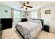 Cozy bedroom featuring a floral bedspread, tiled floor, a ceiling fan and natural light from the windows at 2141 Holiday Dr, Holiday, FL 34691