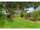 Spacious, well-maintained backyard with lush green grass, mature trees, and a screened-in porch at 23302 Lucerne Pl, Land O Lakes, FL 34639