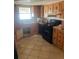 Classic kitchen featuring tile floors, wood cabinets, and black appliances at 3238 Coldwell Dr, Holiday, FL 34691
