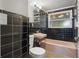Retro bathroom featuring black tile walls, a pink sink, bathtub, and modern flooring at 34577 Orchid Pkwy, Dade City, FL 33523