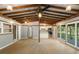 Open-concept living area with a wood-beam ceiling, modern floors, and access to the kitchen and the outdoors at 34577 Orchid Pkwy, Dade City, FL 33523