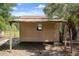 Exterior view of shed with wood siding, weathered awning, and small window under a blue sky with some surrounding foliage at 34577 Orchid Pkwy, Dade City, FL 33523