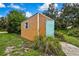 Exterior view of brown shed with a light-blue door and window in a grassy area, ideal for storage at 364 Waterfall Dr, Spring Hill, FL 34608