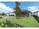 Landscaped backyard with lush green grass, a screened-in lanai, and black metal fencing offers privacy and space at 3885 Villamore Ln, Odessa, FL 33556