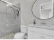 Modern bathroom showcasing a glass-enclosed shower, circular mirror, and a white vanity with stone countertops at 4026 Bonfire Dr, Odessa, FL 33556