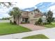 The front exterior of a tan two-story house with a two-car garage and manicured landscaping at 4026 Bonfire Dr, Odessa, FL 33556