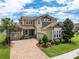 Charming two-story home featuring a brick driveway, mature landscaping, and a welcoming front porch at 4026 Bonfire Dr, Odessa, FL 33556