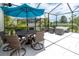 Relaxing outdoor seating area with an umbrella and comfortable wicker furniture in a screened in enclosure at 4026 Bonfire Dr, Odessa, FL 33556