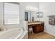 Bright bathroom showcasing vanity with granite counters, vanity mirrors, soaking tub, and tile floors at 4481 Birchfield Loop, Spring Hill, FL 34609