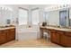 Well-lit bathroom showcasing double sinks with granite counters, tiled floors, and a luxurious soaking tub at 4481 Birchfield Loop, Spring Hill, FL 34609