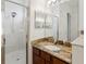 Bright bathroom featuring tiled shower with glass doors, granite counter, and a large vanity mirror at 4481 Birchfield Loop, Spring Hill, FL 34609