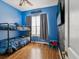 Bright bedroom with hardwood flooring, bunk beds, a window, and a TV on the wall at 4481 Birchfield Loop, Spring Hill, FL 34609