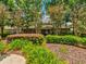 Well-manicured landscaping frames the exterior of the clubhouse featuring flowering trees and decorative bushes at 4481 Birchfield Loop, Spring Hill, FL 34609