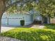 Inviting exterior showcasing a three-car garage, lush lawn, and well-maintained landscaping at 4481 Birchfield Loop, Spring Hill, FL 34609