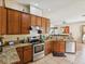 Well-equipped kitchen with stainless steel appliances, tile floors, and wooden cabinets at 4481 Birchfield Loop, Spring Hill, FL 34609