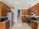 Well-equipped kitchen with stainless steel appliances, tile floors, and wooden cabinets at 4481 Birchfield Loop, Spring Hill, FL 34609
