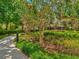 Scenic walking path through lush landscaping leading to the clubhouse with flowering trees and benches at 4481 Birchfield Loop, Spring Hill, FL 34609