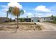 Single-story house with a well-manicured lawn, light blue garage door, and a lush palm tree in the front yard at 5321 Mosaic Dr, Holiday, FL 34690