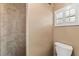 Tiled walk-in shower with toilet and a window with white shutters at 5502 Bluejay Ln, Tampa, FL 33625