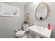 Bathroom featuring a toilet, pedestal sink and a round mirror above at 5502 Bluejay Ln, Tampa, FL 33625