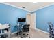 Functional home office featuring a glass desk, blue walls, and ample space for productive work sessions at 5502 Bluejay Ln, Tampa, FL 33625