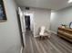 Hallway view featuring wood-look flooring and a decorative accent chair, leading to the bathroom at 5555 Gulf Blvd # 315, St Pete Beach, FL 33706