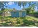 Blue storage shed with a white door sits in the grassy backyard under a large tree at 5724 Casson Ave, New Port Richey, FL 34652