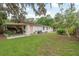 Exterior view of a home featuring a covered patio, manicured lawn, and mature trees at 6019 Wyoming Ave, New Port Richey, FL 34653