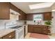 Well-lit kitchen with white appliances, brown cabinets, and a skylight providing natural light at 6019 Wyoming Ave, New Port Richey, FL 34653