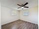 Bright bedroom featuring wood-look flooring, a ceiling fan, and two windows at 6341 Hyperion Dr, Port Richey, FL 34668