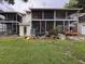 Exterior view of backyard with brick landing with potted plants and screened in porch at 7133 Trenton Pl, New Port Richey, FL 34653
