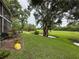 Large backyard features mature trees and a pond with view of the screened in porch at 7133 Trenton Pl, New Port Richey, FL 34653
