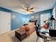 A blue bedroom featuring a ceiling fan, a comfortable bed, and a cozy desk area at 7133 Trenton Pl, New Port Richey, FL 34653