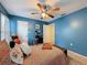 Blue bedroom showcasing a ceiling fan, light hardwood floors, and a stylish desk area at 7133 Trenton Pl, New Port Richey, FL 34653