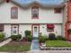 Charming townhouse featuring well-manicured landscaping, a white facade, and red brick trim at 7133 Trenton Pl, New Port Richey, FL 34653