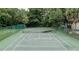 An outdoor tennis court surrounded by a green fence and mature trees, offers recreation and privacy at 7133 Trenton Pl, New Port Richey, FL 34653