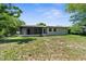 Back exterior view of the home and screened in patio, surrounded by large trees at 7192 Catalina St, Spring Hill, FL 34606