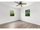 Bright bedroom featuring wood-look floors, two windows, and a ceiling fan at 7192 Catalina St, Spring Hill, FL 34606