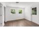 Bright living room featuring wood-look flooring, white walls, and two windows for natural light at 7192 Catalina St, Spring Hill, FL 34606