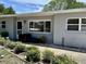 Inviting single-story home with neutral gray exterior, well-maintained landscaping, and cozy front seating area at 723 W Bayshore Dr, Tarpon Springs, FL 34689
