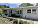 Inviting single-story home with neutral gray exterior, well-maintained landscaping, and cozy front seating area at 723 W Bayshore Dr, Tarpon Springs, FL 34689