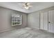 Neutral carpeted bedroom with fan, window, and closet doors at 7423 Woodhollow Rd, Spring Hill, FL 34606