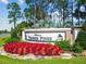 Welcome to Timber Pines sign surrounded by lush landscaping and vibrant flowers at 7423 Woodhollow Rd, Spring Hill, FL 34606