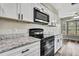 Modern kitchen with stainless steel microwave, oven and white cabinets with dark hardware at 7423 Woodhollow Rd, Spring Hill, FL 34606