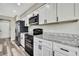 Contemporary kitchen featuring sleek black appliances, granite counters and white cabinets at 7423 Woodhollow Rd, Spring Hill, FL 34606